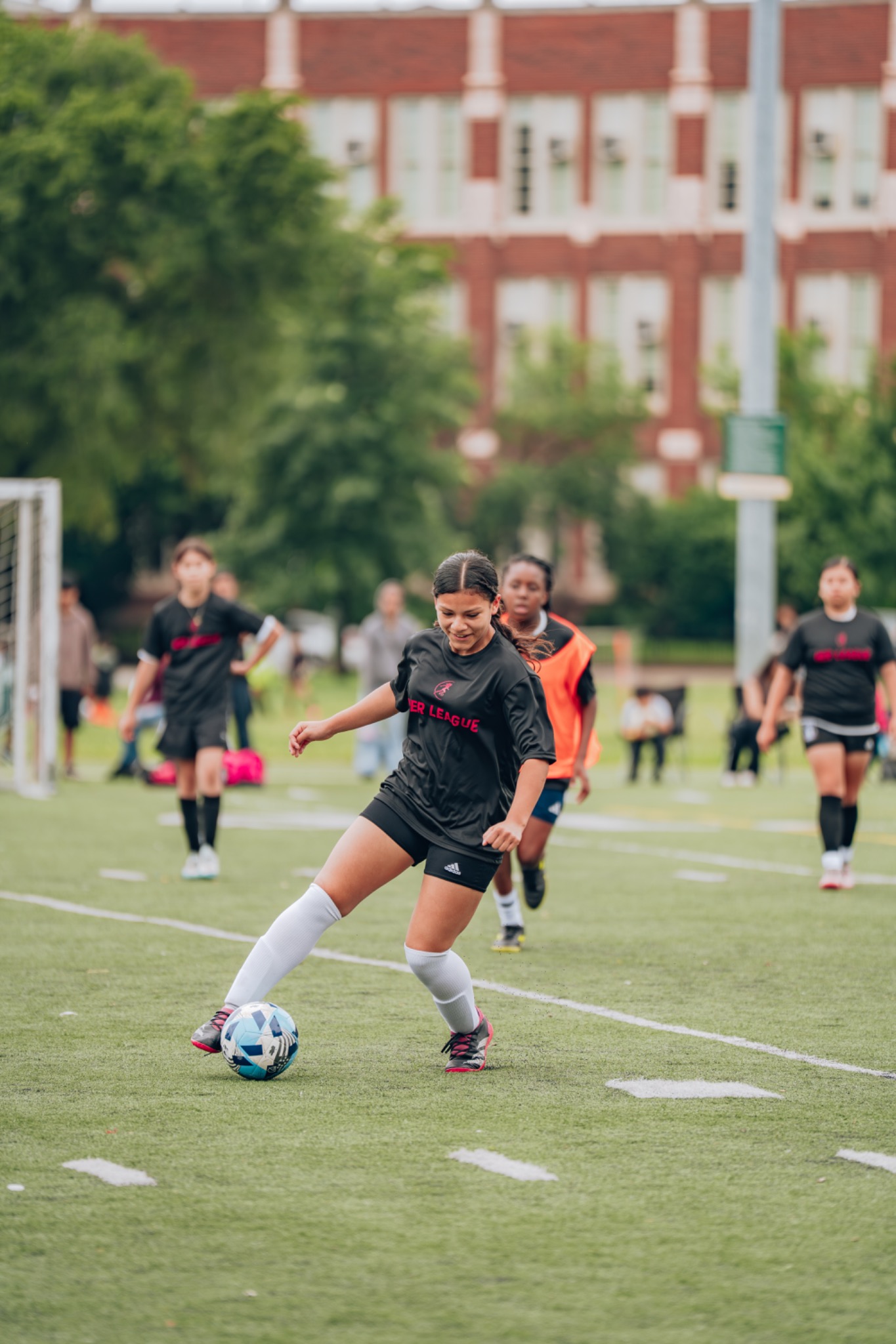 A HER League player controlling the ball during a soccer game
