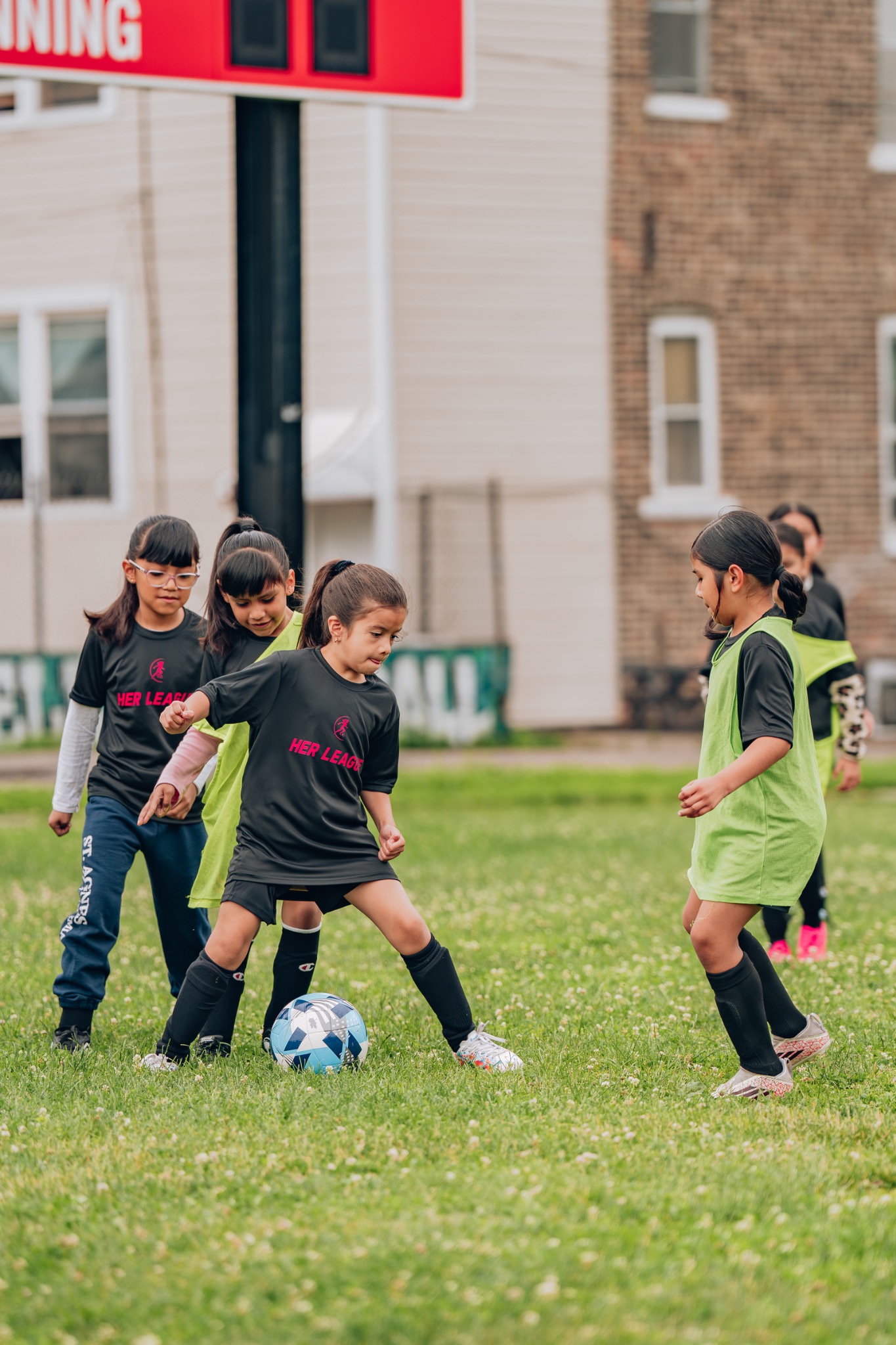 HER League girls playing soccer together during a community game